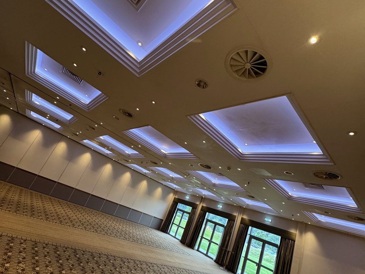 A hotel function room with lit ceiling coffers and downlights