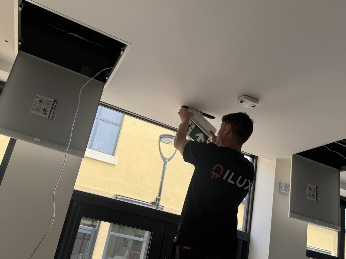 An ILUX engineer on a ladder working on a fitting