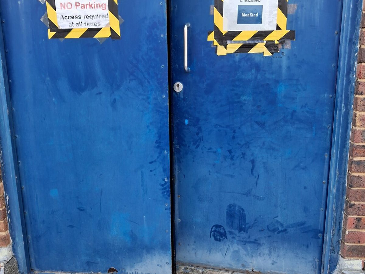 A pair of steel back-of-house doors with worn frames awaiting repair