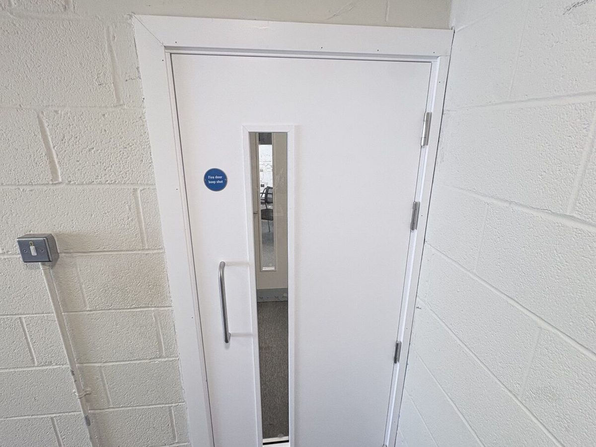 New single fire doorset with vision panel and pull handle installed in a blockwork wall