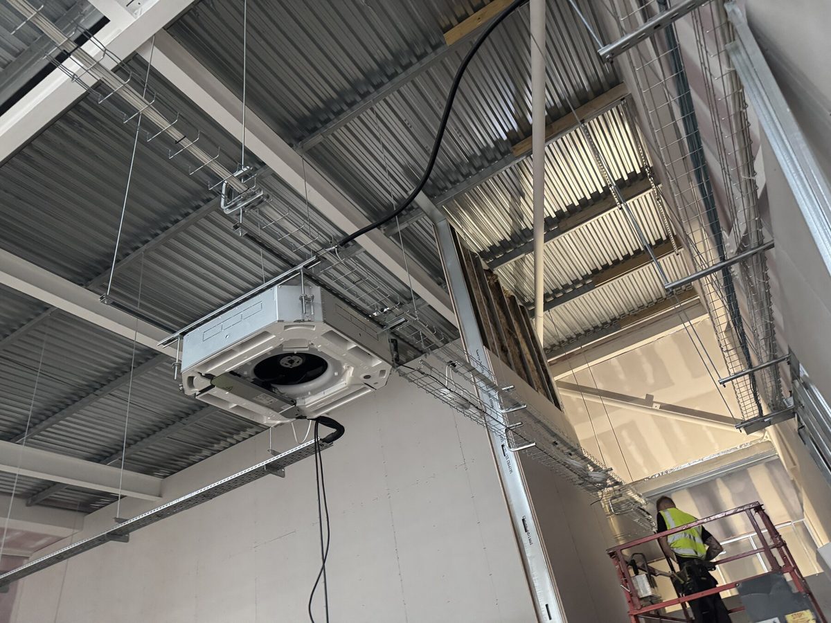 An engineer on a lift installing services during a fit-out