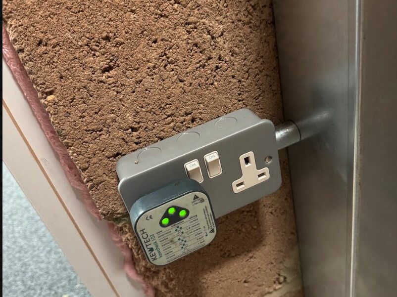 A socket tester plugged into a wall socket