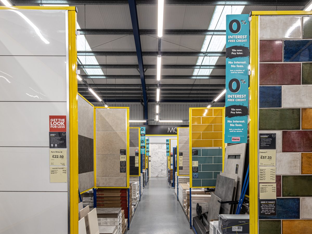 An aisle of tile display boards in reds, greens, blues and ochres under the new LED lighting